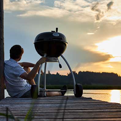 Holzkohle Kugelgrill Holzkohle Kugelgrill auf Steg mit Sonnenuntergang