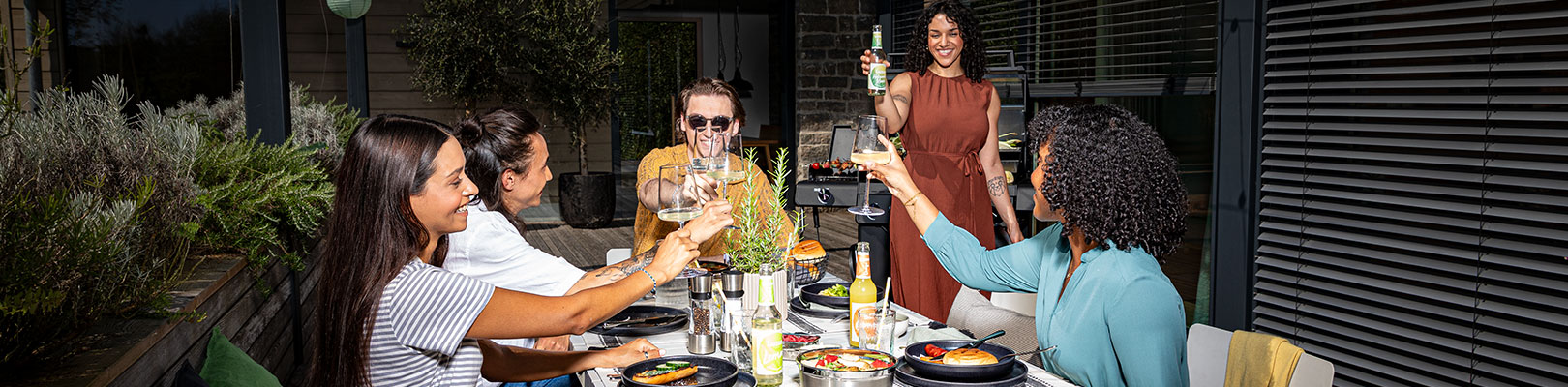 Friends sit together on the terrace and clink glasses