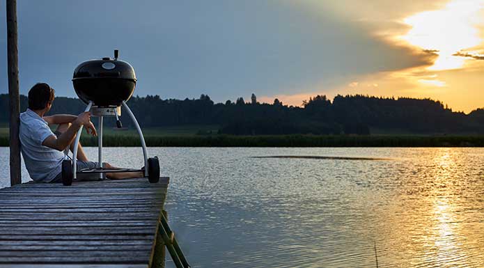 Holzkohle Kugelgrill Holzkohle Kugelgrill auf Steg mit Sonnenuntergang