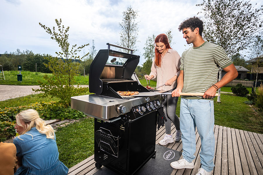 Freunde grillen zusammen Pizza auf einem Pizzastein