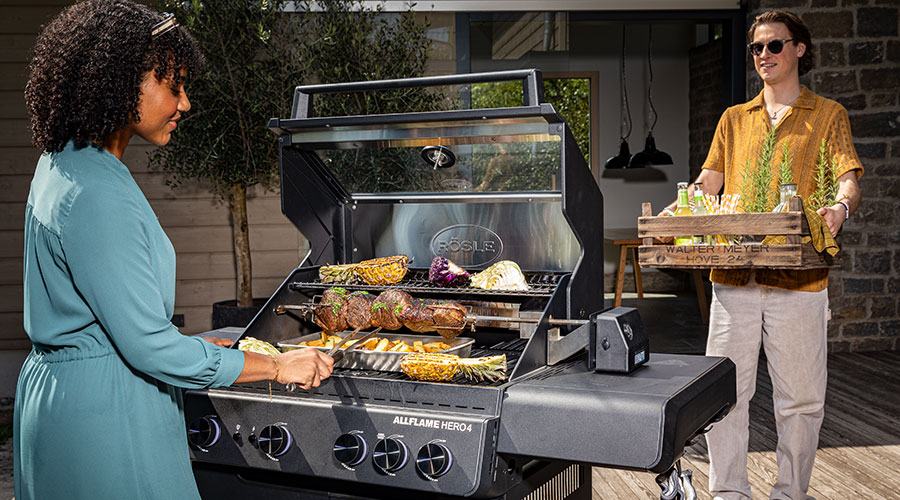 Allflame Hero 4 Woman grilling on the barbecue and man carrying tray with drinks