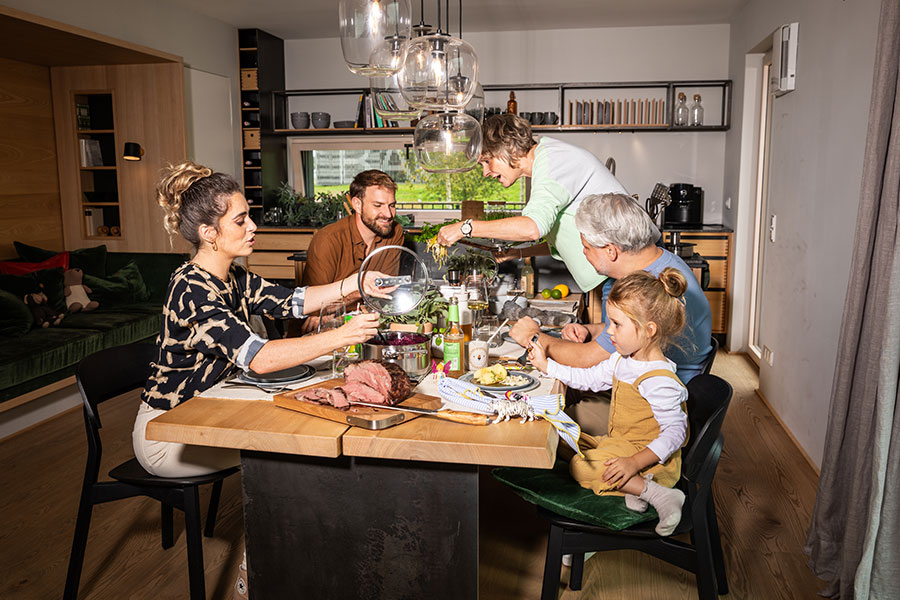 Familie isst gemeinsam einen Braten am Tisch.