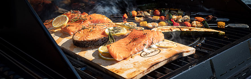Header Versand und Zahlung Lachs wird auf Räucherplanke auf dem Grill gegrillt