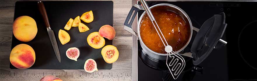 Saucepan Silence Pro 20 cm Peaches and figs on the cutting rest next to the Silence Pro saucepan 20 cm with jam