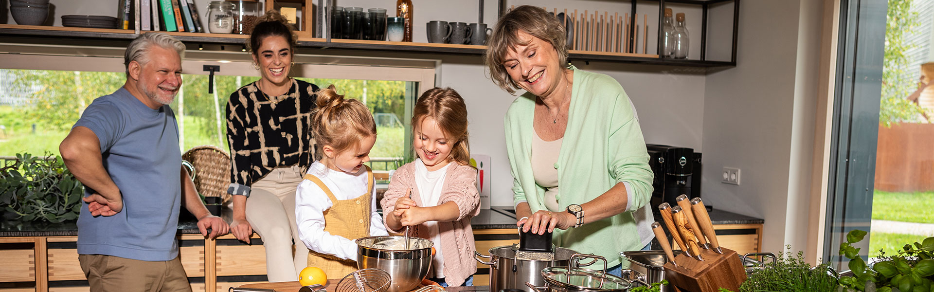 Kinder backen zusammen mit Oma während Mutter und Opa zuschauen