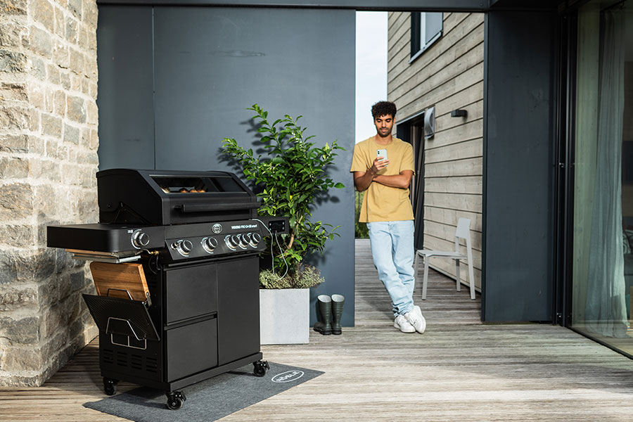 Mann fotografiert seinen Grill mit dem Handy