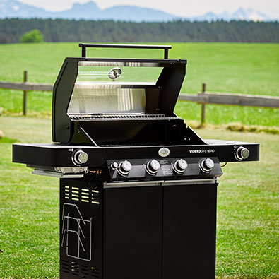 Gasgrill Videro G4-S NERO mit geöffnetem Deckel im Garten.